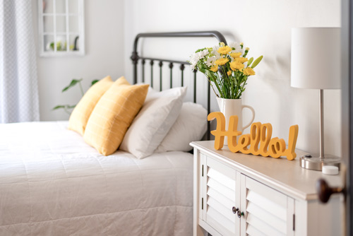 A bedroom with a Hello sign on the side table